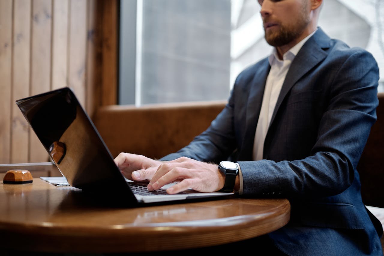 A focused businessman in a suit working on a laptop in a modern office setting.